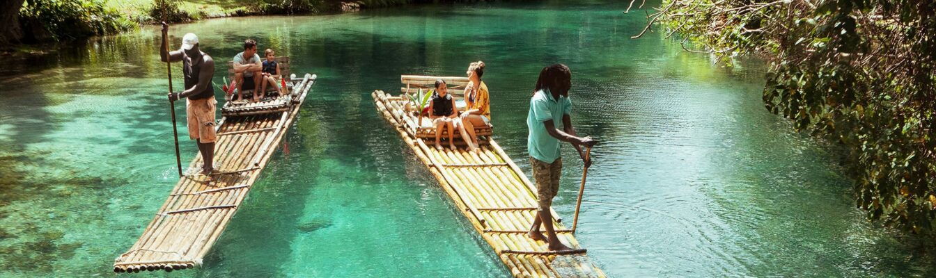 Man rowing bamboo raft, Martha Brae. Tourist boy whilst on cruis